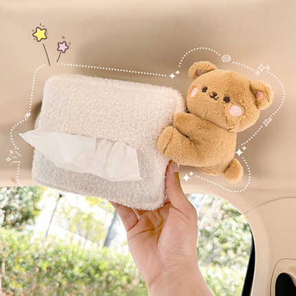 A hand holds a plush, cream-colored car tissue box with a cute teddy bear attached, perfect for adding charm to your vehicles...