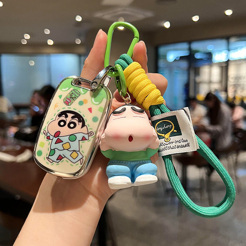 A hand holds a wuling hongguang mini ev car key cover featuring a cartoon design with a green and yellow rope strap, perfect ...