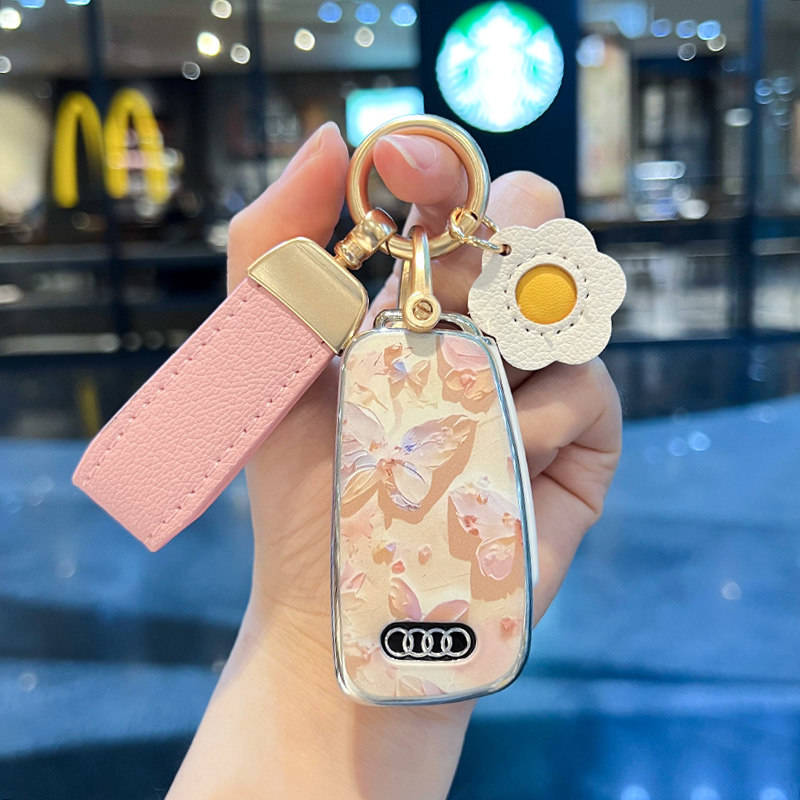 Elegant audi a6l key cover featuring a floral design with butterflies, paired with a pink leather strap and a decorative flow...
