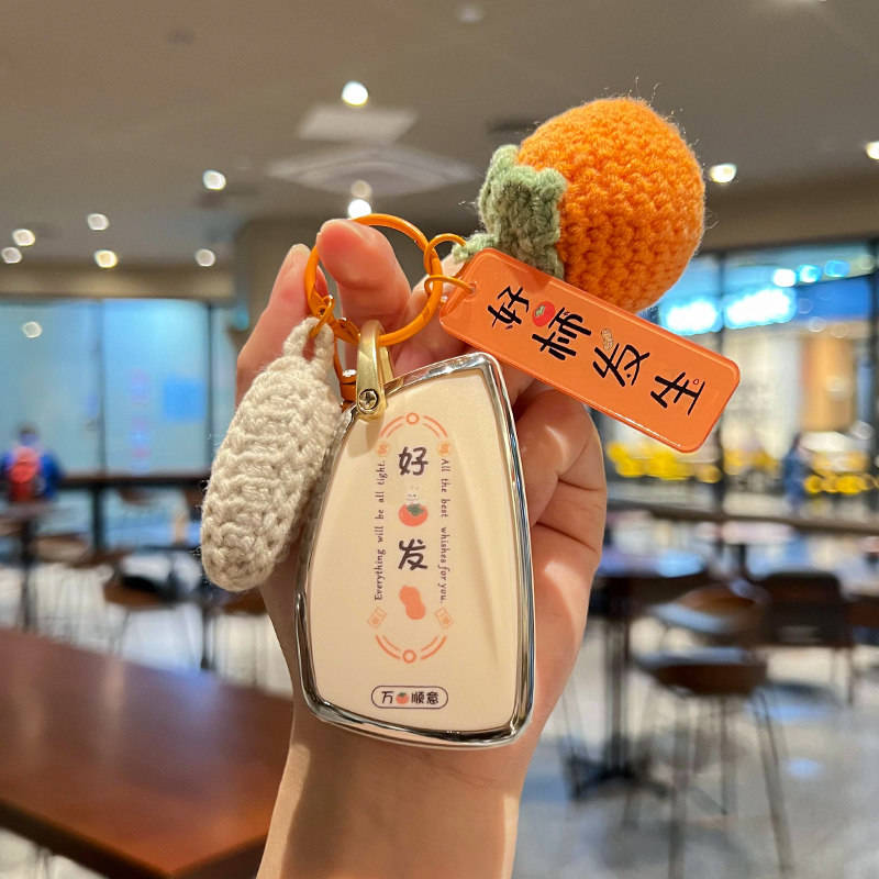 A hand holds a stylish buick enclave plus car key cover with a leather shell case, featuring a good luck design and a crochet...