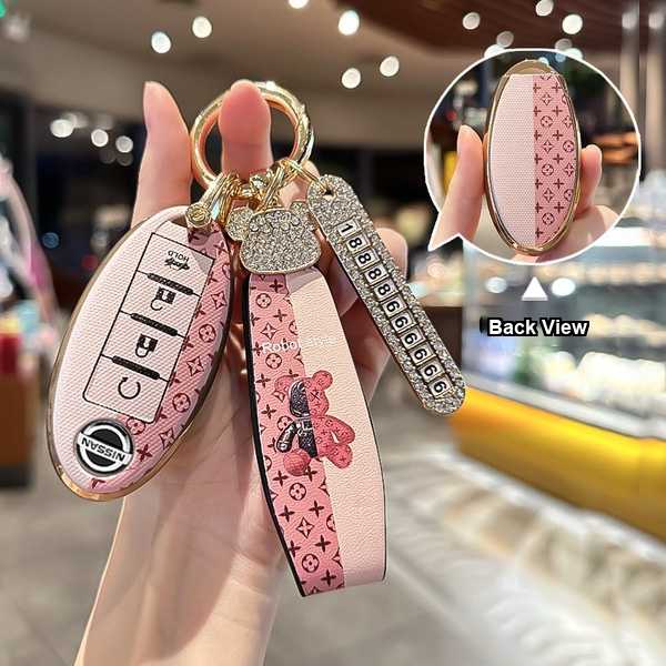 Elegant nissan key cover featuring a pink monogram design with a sparkling teddy bear charm, perfect for x-trail, altima, qas...