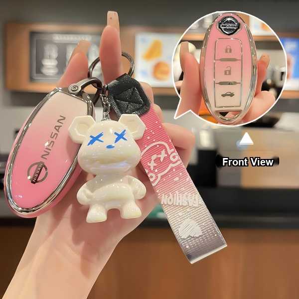 A hand holds a pink nissan key cover with a cute bear charm, showcasing its front view and sleek design for sylphy, teana, x-...
