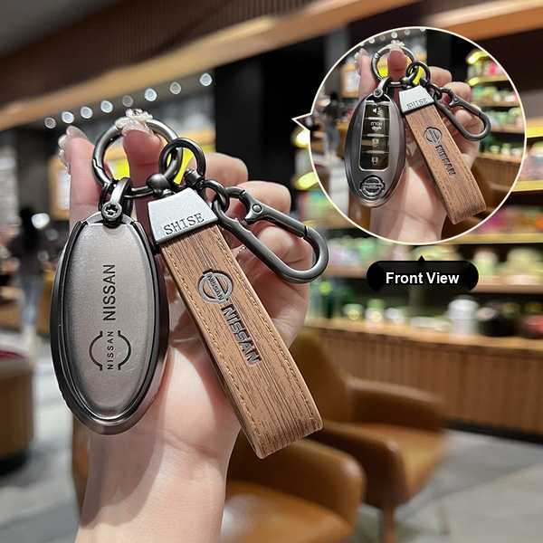Hand holding a nissan key cover with leather strap, designed for 14th-gen sylphy, x-trail, and teana, shown in front view wit...