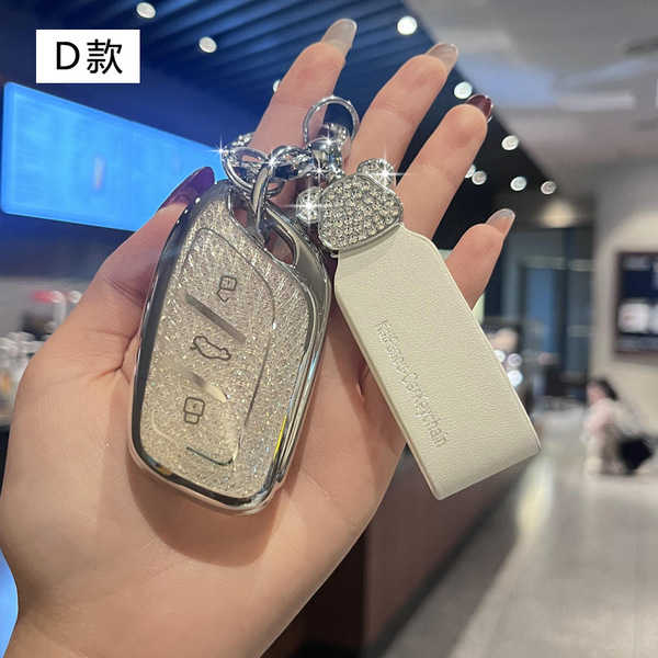 Hand holding a roewe i5 key cover with sparkling design and leather tag, showcasing premium protection and style.