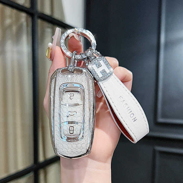 A hand holds a sleek, silver geely key cover with a leather strap labeled fashion, designed for models like emgrand gs and bo...