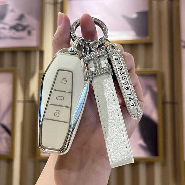 Elegant white icar 03 key cover with leather strap and decorative keychain, designed for eq7 shuxiangjia 2024, featuring a sl...