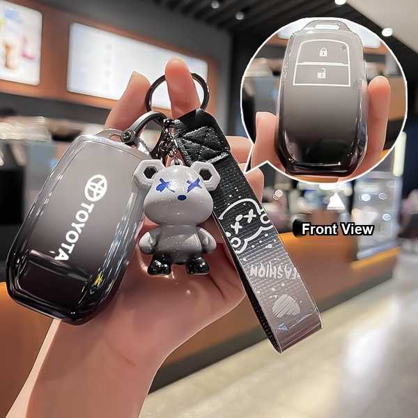 Hand holding a sleek toyota crown kluger key cover with a stylish bear charm and front view inset showcasing its design.