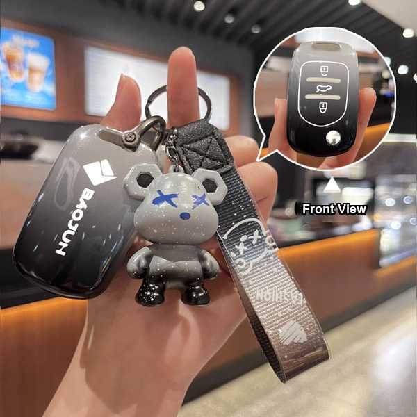 Hand holding a baojun 730 key cover with a stylish bear charm and front view inset, showcasing premium leather design for sma...