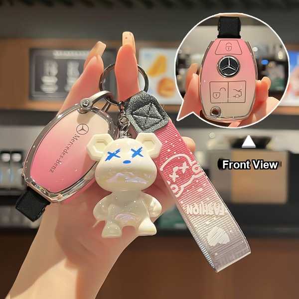 A hand holds a pink mercedes-benz key cover for models like the e300, c260, a200, c200, gla, and glc, featuring a cute bear c...