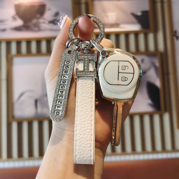 Elegant suzuki swift alto jimny key cover featuring a sleek white design with a leather strap and a decorative number plate, ...