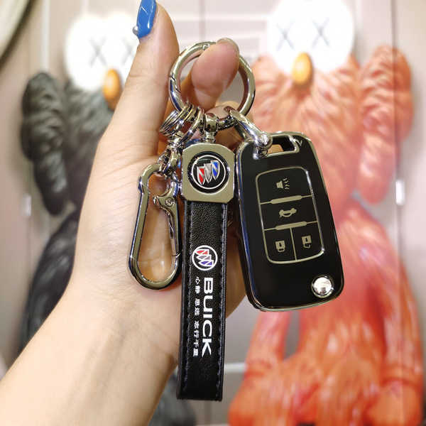 A hand holds a sleek black buick key cover for excelle, encore, regal, and gl8 models, featuring a carabiner and leather stra...
