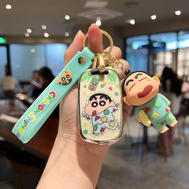 A hand holds a wuling hongguang mini ev car key cover featuring a cartoon design with a character in colorful pajamas, accomp...