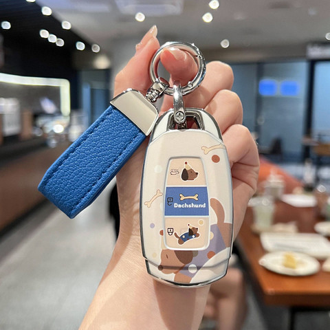 A hand holds a hyundai elantra car key cover featuring a slim silicone shell case with a playful dachshund design, including ...