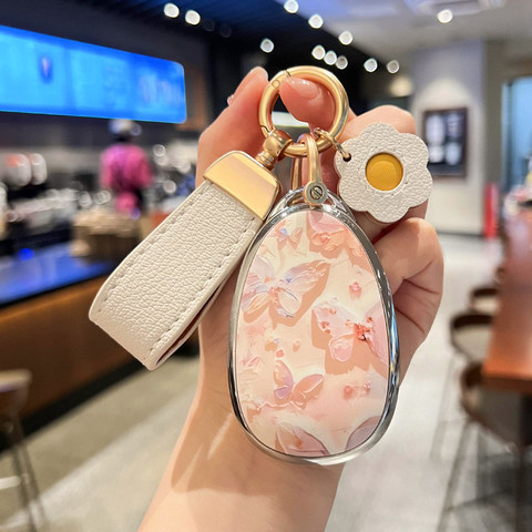Elegant changan qiyuan a07 key cover featuring a floral design with butterflies, complemented by a leather strap and decorati...