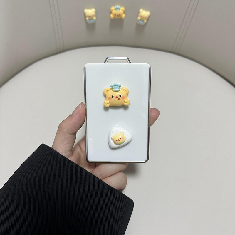 A hand holds a white im ls6 ls7 car key cover featuring cute bear designs, including one with a chef hat and another on a hea...
