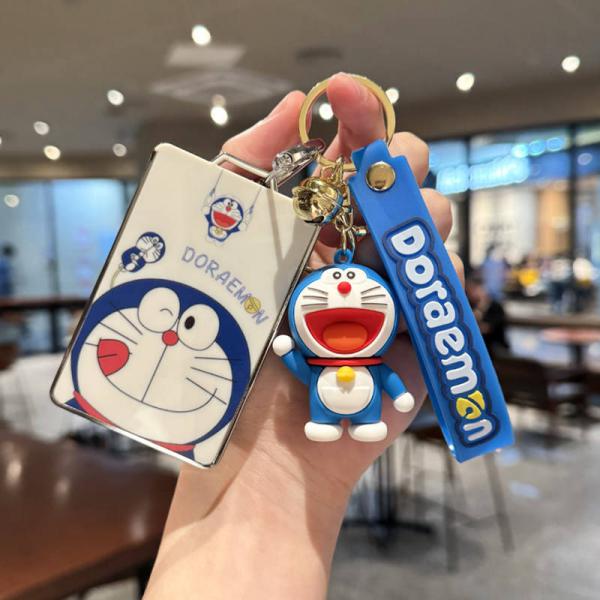 A hand holds a buick e5 card key cover featuring a doraemon design, paired with a matching doraemon keychain and strap, showc...