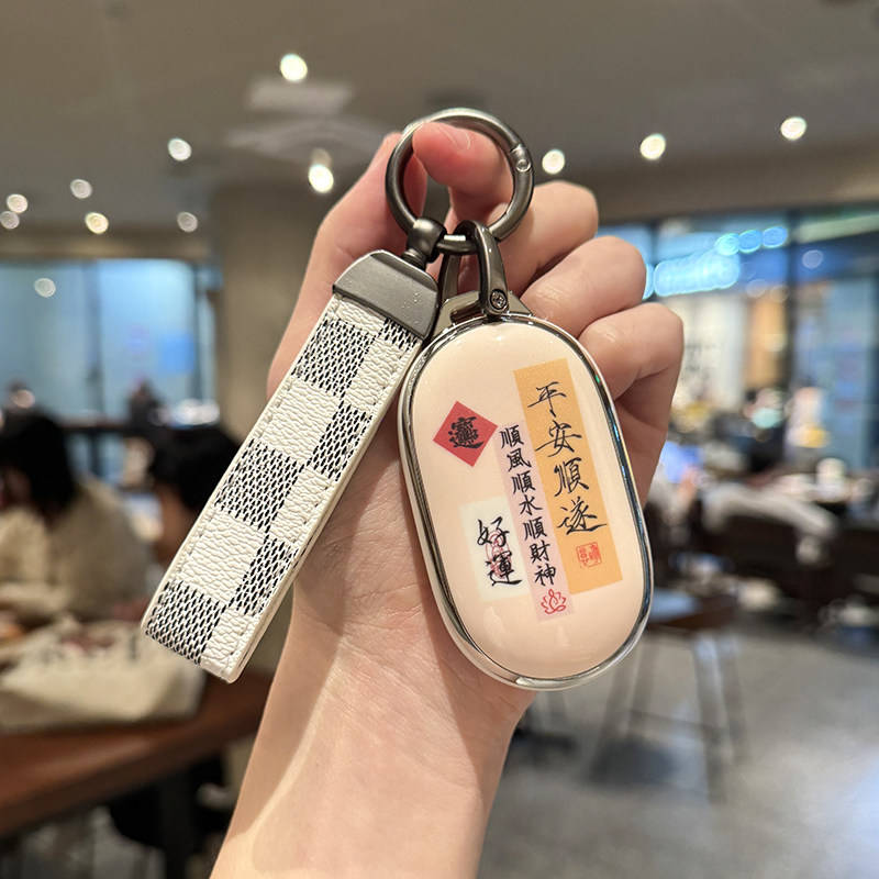 A hand holds a stylish geely geometry starry wish key cover, featuring a white and black checkered strap and a beige shell ca...