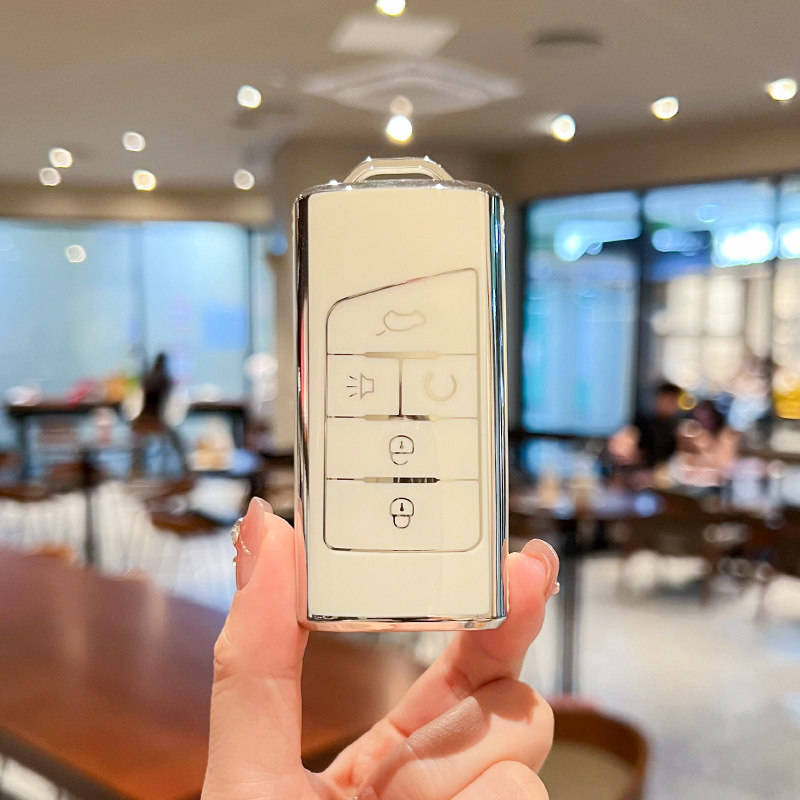 A hand holds a sleek, metallic gac trumpchi gs4 car key cover with a pu leather shell case, featuring buttons for lock, unloc...