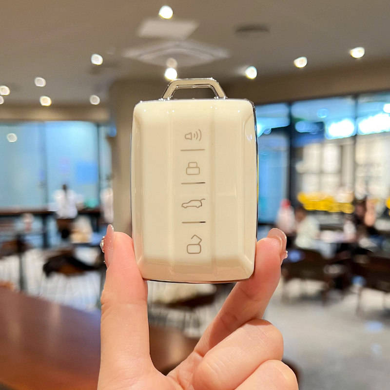 A hand holds a sleek, cream-colored tank 300 car key cover, featuring icons for lock, unlock, and trunk release, designed for...