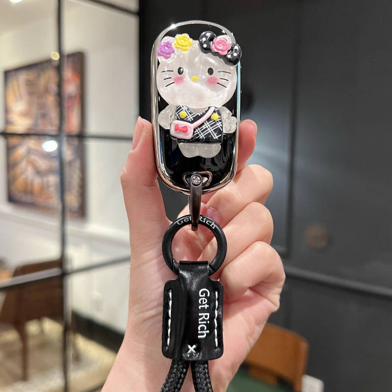 A hand holds a stylish buick velite pro car key cover featuring a hello kitty design with floral accents and a get rich leath...