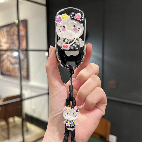 A hand holds a stylish buick regal car key cover featuring a cute hello kitty design with floral accents and a matching keych...