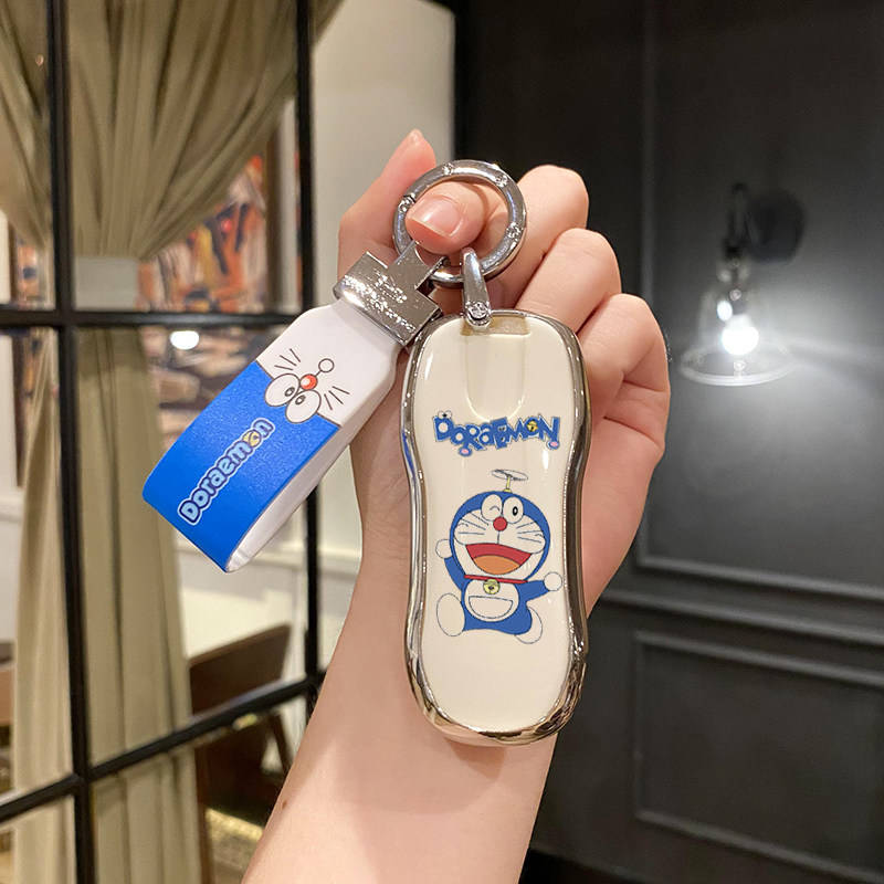 A hand holds a stylish porsche car key cover featuring a doraemon design, perfect for cayenne, panamera, macan, 911, taycan, ...