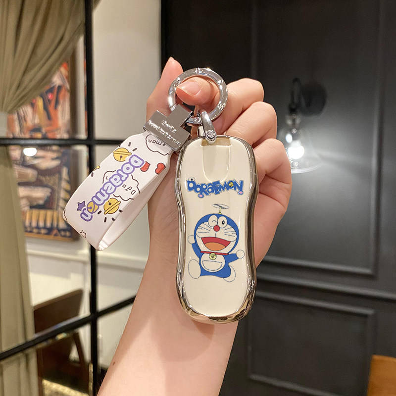 A hand holds a stylish porsche car key cover featuring doraemon, with a matching wrist strap, perfect for cayenne, panamera, ...