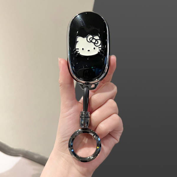 A hand holds a sleek black nio es8 card key cover featuring a white hello kitty design, complete with a metallic key ring and...