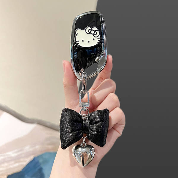 A hand holds a stylish roewe rx5 plus key cover featuring a hello kitty design, adorned with a black bow and a shiny heart ch...