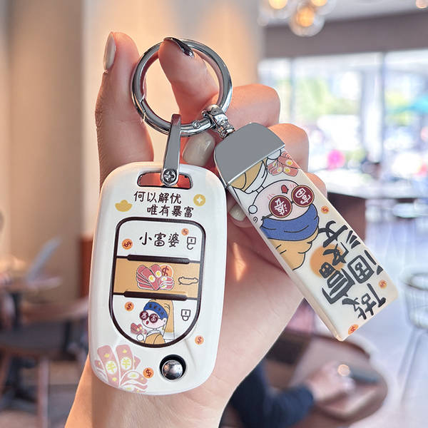 A hand holds a wuling hongguang mini ev key cover featuring a little rich wife cartoon design with playful text and a matchin...