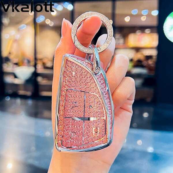 A hand holds a sparkling pink key cover for the buick envision plus 2023, featuring a glittery finish and sleek design.