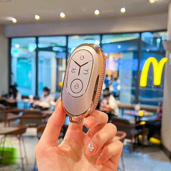 A hand holds a geely xingyuan 2025 key cover, showcasing its elegant gold and white design with a premium pu leather shell, s...