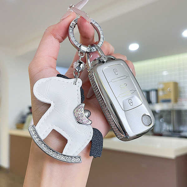 A hand holds a stylish volkswagen jetta vs5 key cover, featuring a silver design with sparkling details and a charming white ...