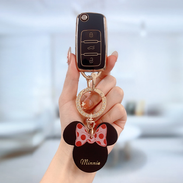 A hand holds a skoda key fob with a premium leather key cover featuring a minnie mouse design, complete with a red polka-dot ...