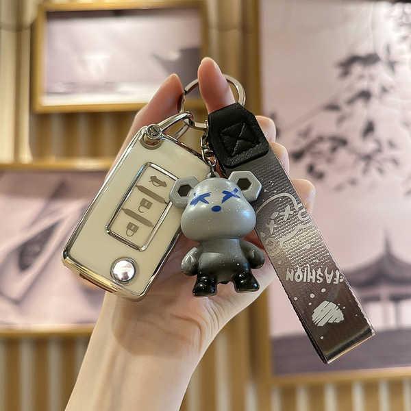 A hand holds a stylish mitsubishi key cover for outlander, eclipse cross & pajero, featuring a cute bear charm and a sleek de...