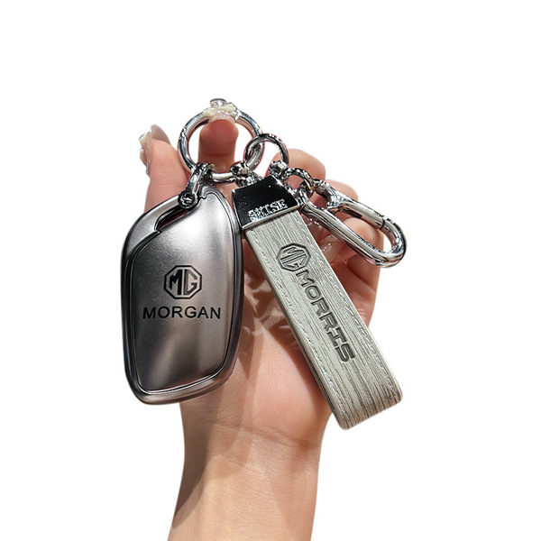 Hand holding a sleek mg5 key cover with gt clasp, featuring a metallic design and morgan branding, perfect for mg3/mg6/zs mod...