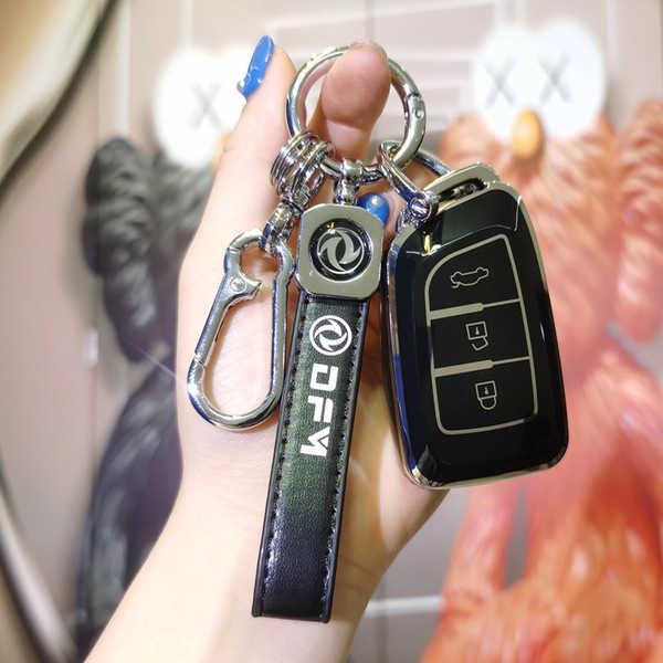 A hand holds a sleek black key cover for the dongfeng ax7, featuring a carabiner and leather strap with the dfm logo, designe...