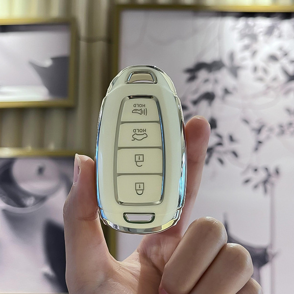 A hand holds a sleek hyundai key cover with silver trim, designed for tucson, elantra, and more, featuring buttons for lock, ...