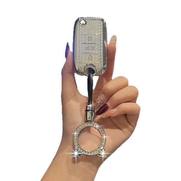 A hand holds a roewe rx5 key cover, showcasing its sleek design with a textured surface and a sparkling ring keychain. this p...