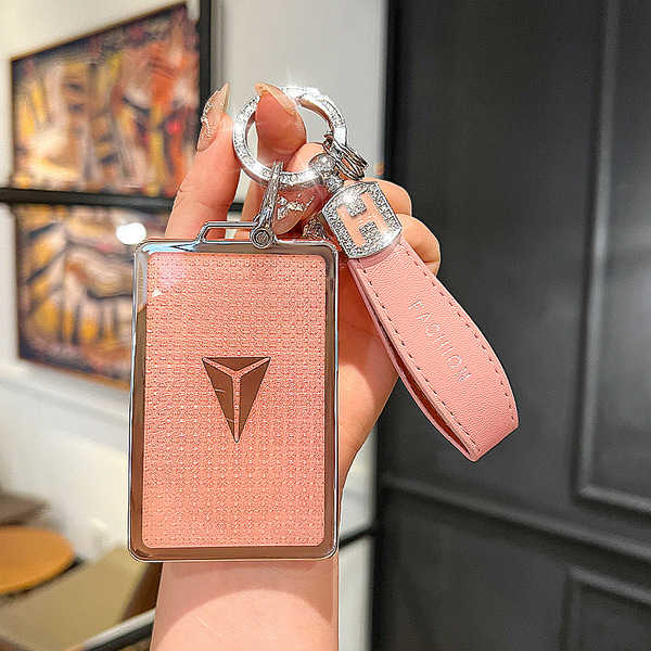 A hand holds a sleek, pink changan sl03 nfc card key cover with a textured finish and a stylish logo, paired with a matching ...
