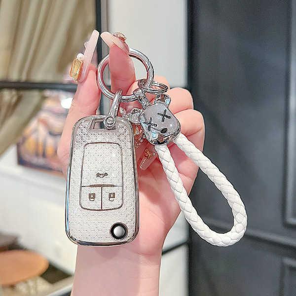 A hand holds a stylish chevrolet key cover for cruze, malibu & trax, featuring a sleek design with a braided white rope and d...