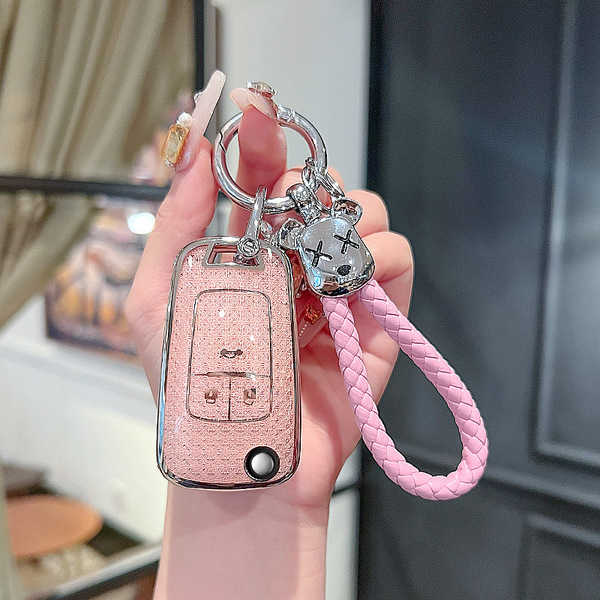 A hand holds a pink chevrolet key cover for cruze, malibu & trax, featuring a glittery finish and a cute bear charm with a br...