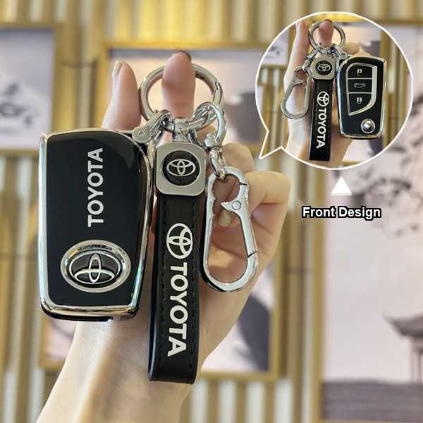 Hand holding a sleek black toyota key cover with front design, featuring the toyota logo and compatible with models like camr...