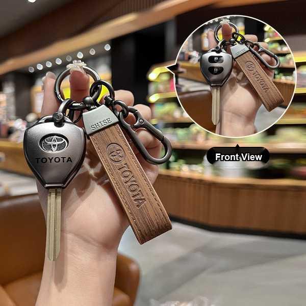 A hand holds a toyota key cover with a wooden-textured strap, featuring the toyota logo and shise branding, shown in a front ...