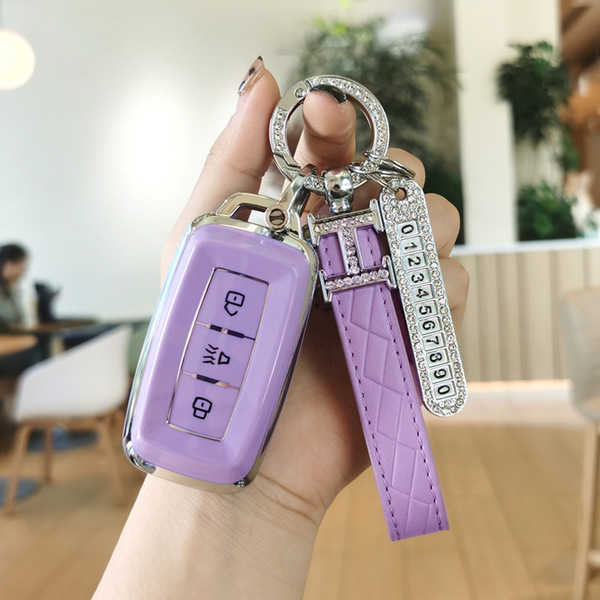 A hand holds a purple chery jetour x70 key cover with a matching strap and a diamond-encrusted keychain, showcasing its elega...
