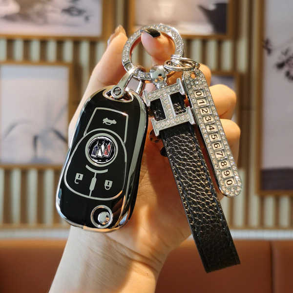 A hand holds a sleek black buick remote key cover for excelle, verano & regal, featuring a diamond-encrusted h keychain and a...