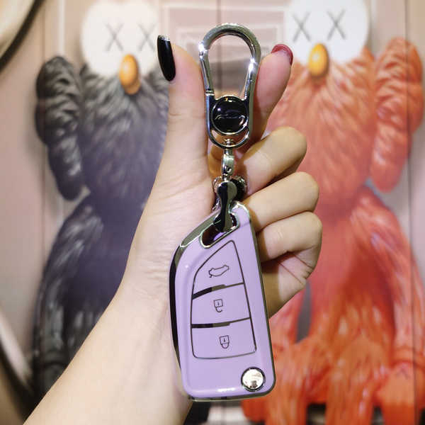 A hand holds a purple vvdi kd blade fold key shell for auto keys, featuring a sleek design with three buttons and a metallic ...