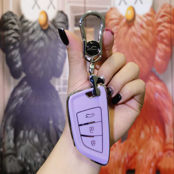 A hand holds a purple vvdi blade-style foldable car key cover, showcasing its sleek design with a metallic keychain, against ...