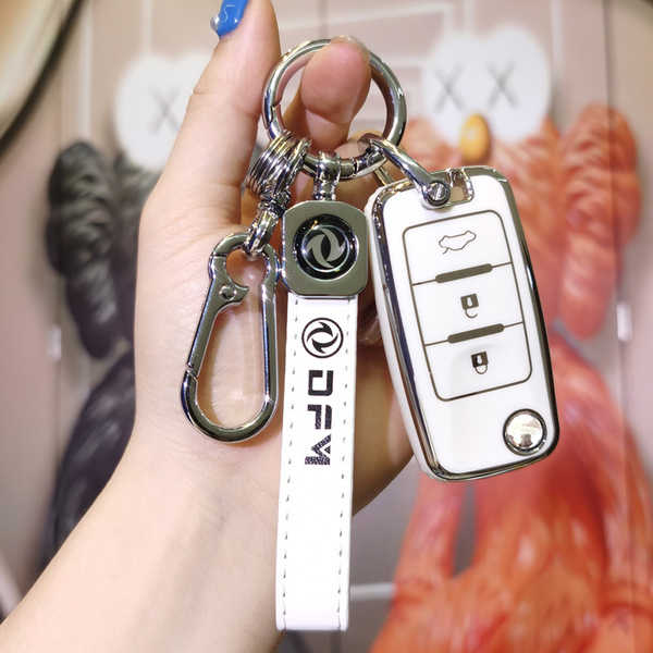 A hand holds a stylish white key cover for the dongfeng fengxing t5, featuring a sleek design with a carabiner and branded st...