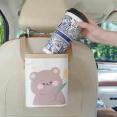 A hand places a patterned cup into a tulip bear car trash can, a cute storage box with a bear design holding a tulip, attache...